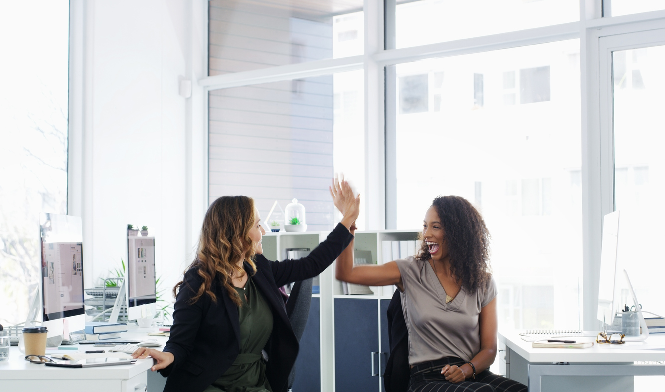 Shot of two young businesswomen giving each other a high five in a modern office